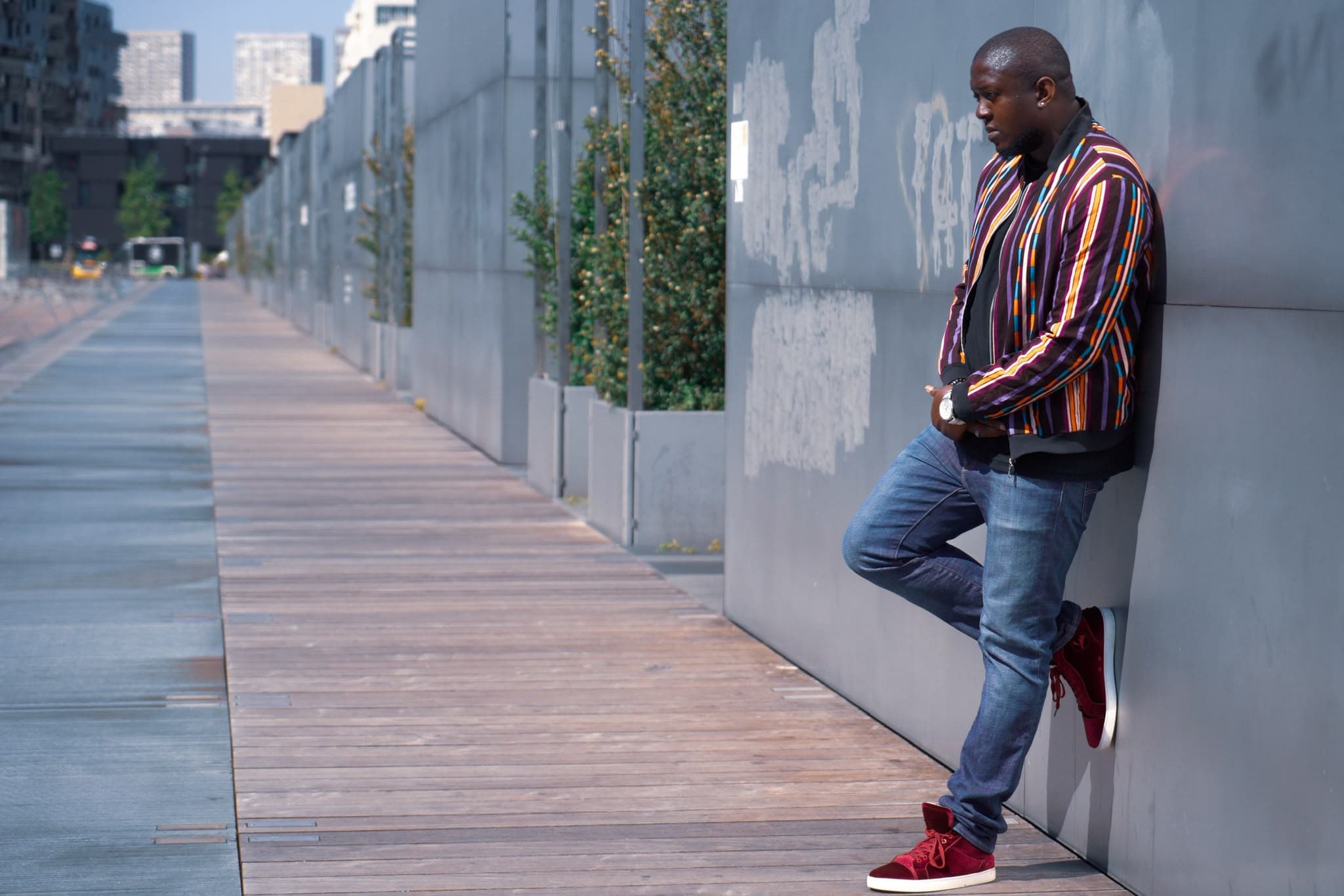 Black Moz en veste rayée, appuyé contre un mur dans une rue de Paris